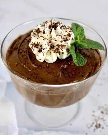 chocolate pudding in glass with whip cream and sprig of mint