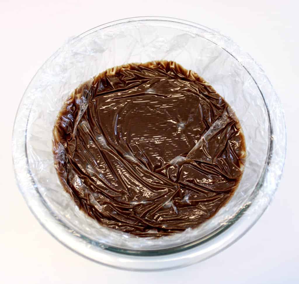chocolate pudding with plastic wrap on top in glass bowl