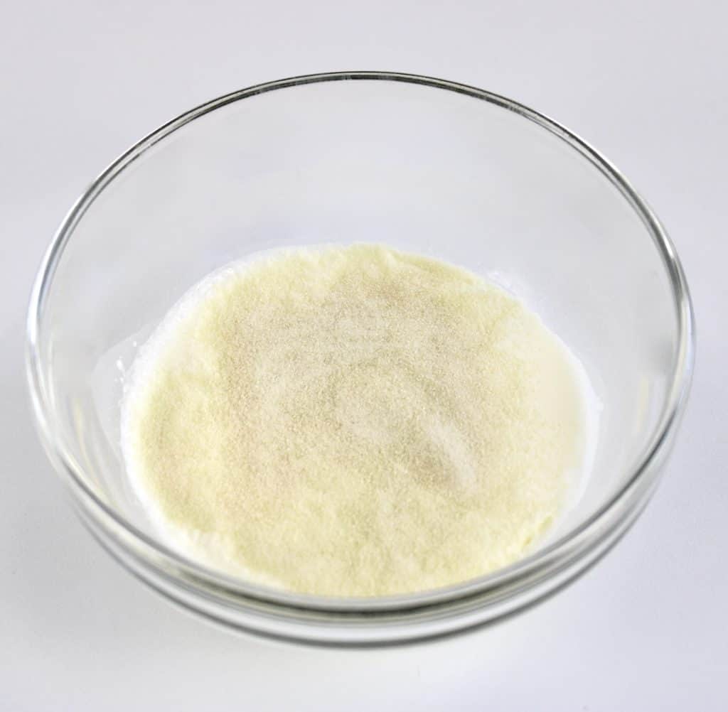 heavy cream with gelatin powder on top in glass bowl