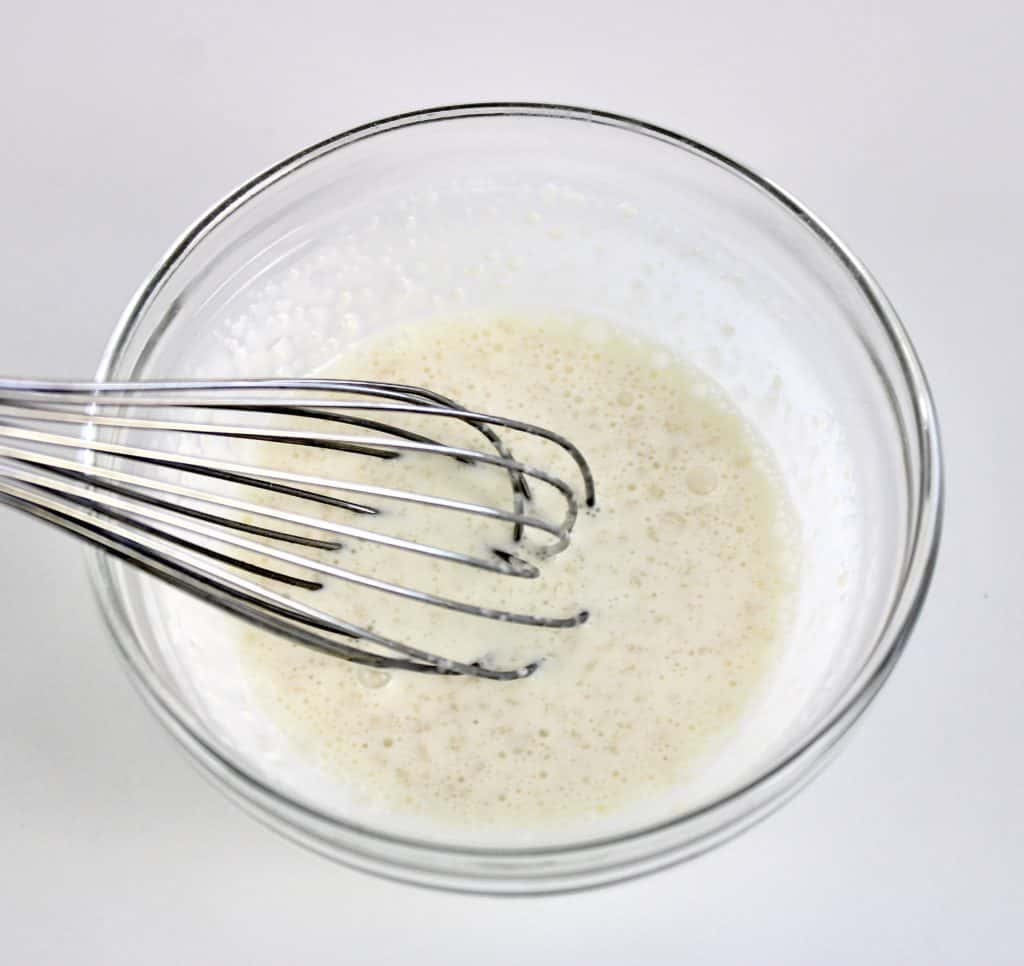 heavy cream with whisk in glass bowl