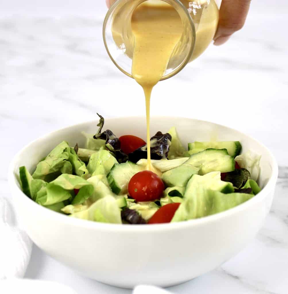 honey mustard being poured over salad