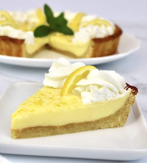 Keto Lemon Mascarpone Tart on white plate with whip cream and lemon slice