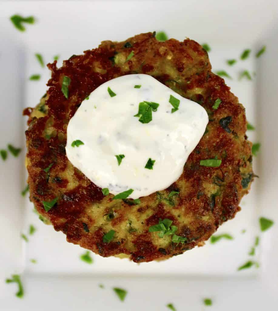 overhead view of zucchini fritter with dipping sauce on top