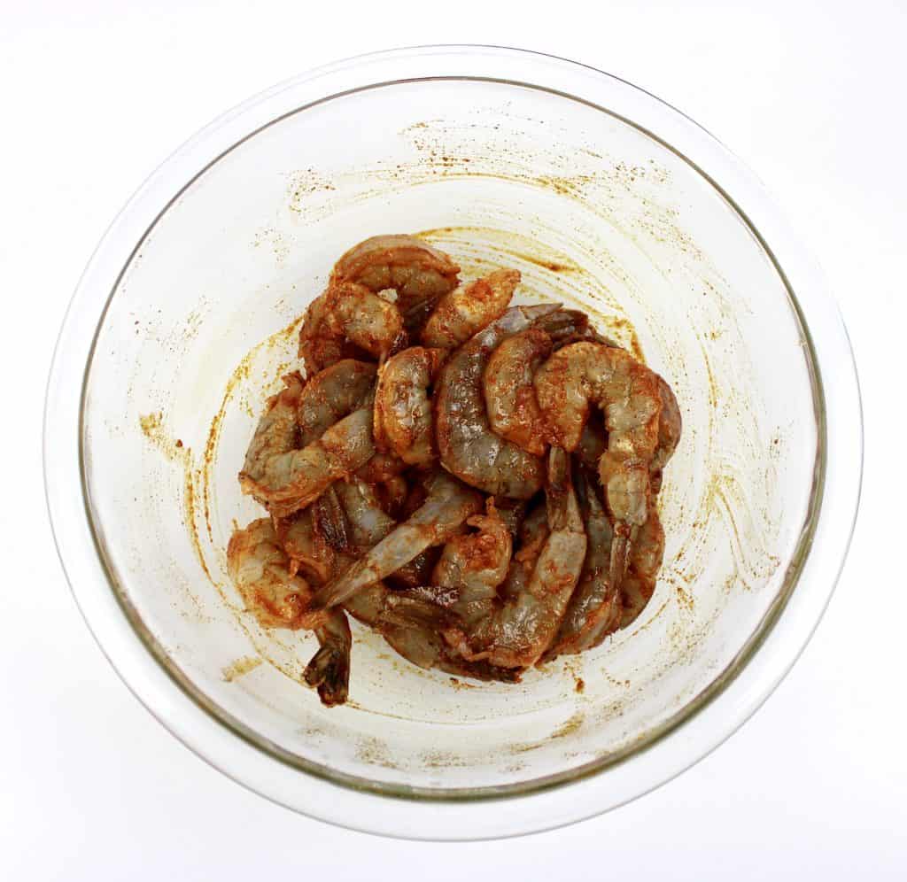 raw shrimp with blackened seasoning in glass bowl