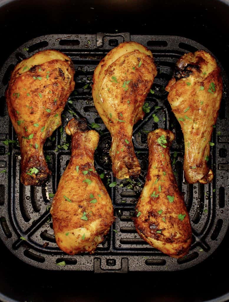 overhead view of 5 chicken legs in air fryer