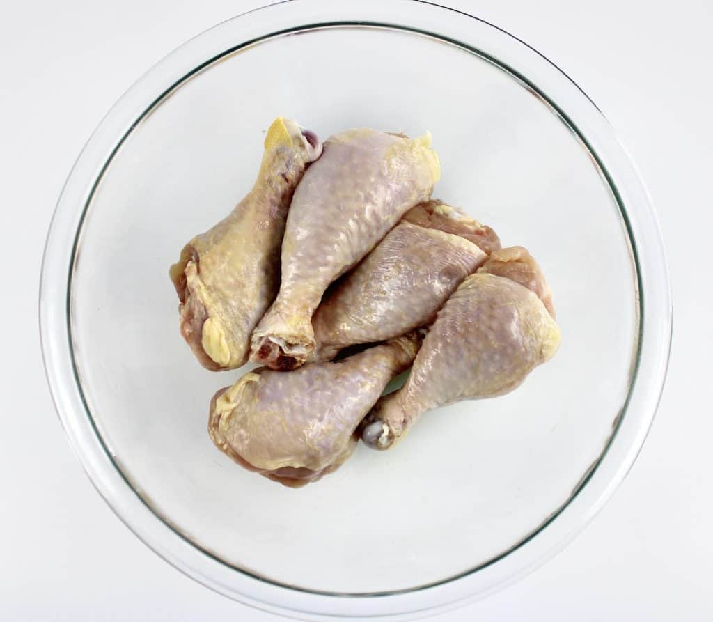 chicken legs in glass bowl with olive oil