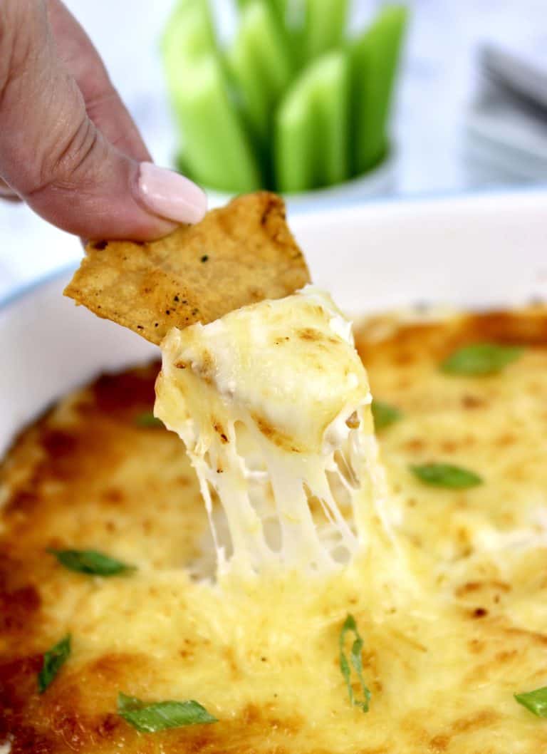 tortilla chip being dipped into crab rangoon dip