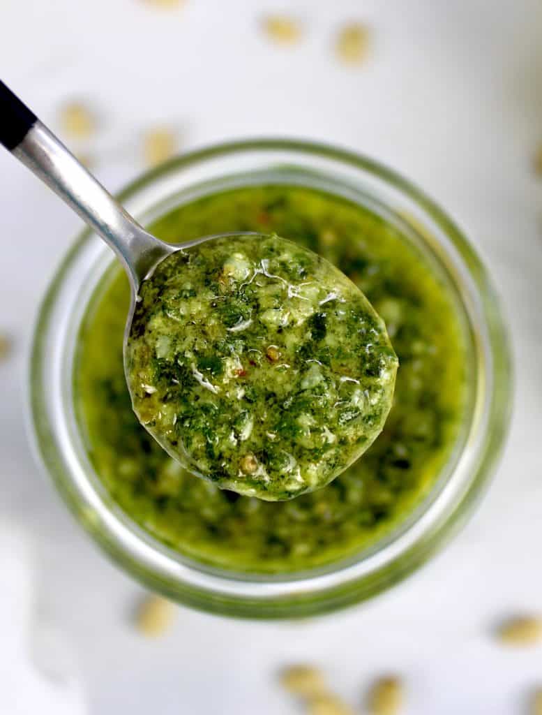closeup overhead view of pesto sauce being spooned out of jar