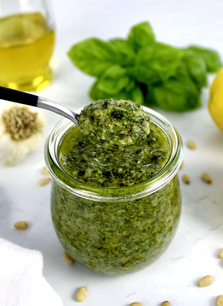 basil sauce being spooned out of glass jar