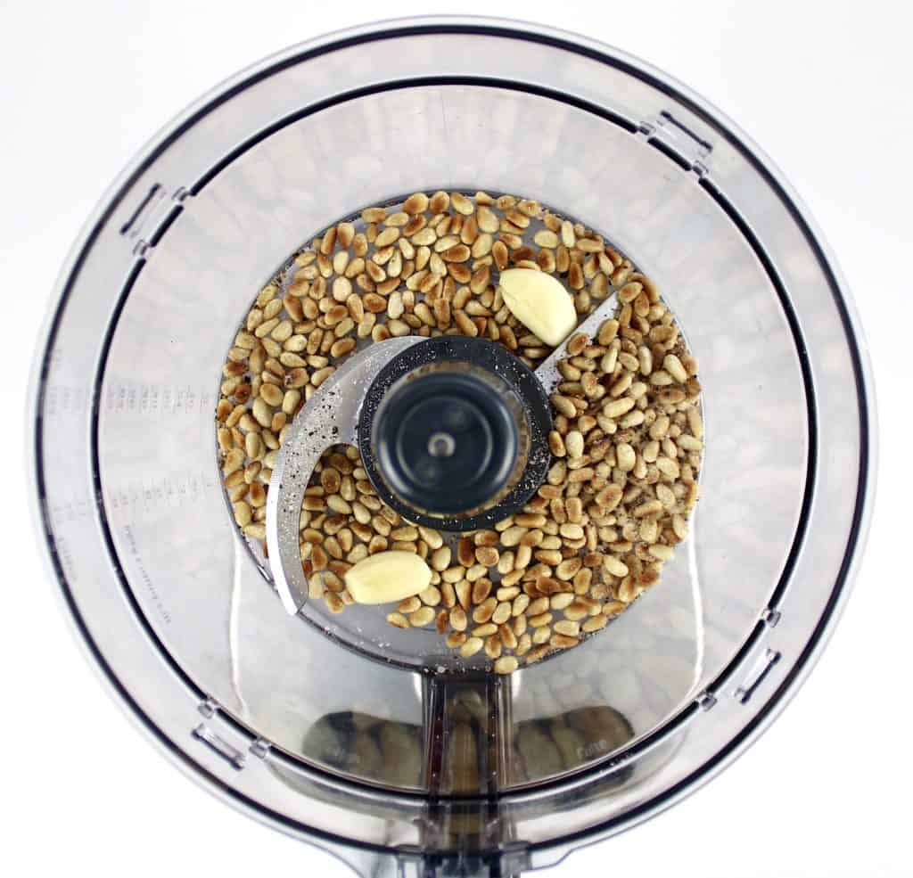 pine nuts and garlic cloves in food processor bowl