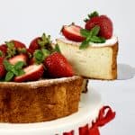 slice of angel food cake with strawberries on top being removed from cake stand