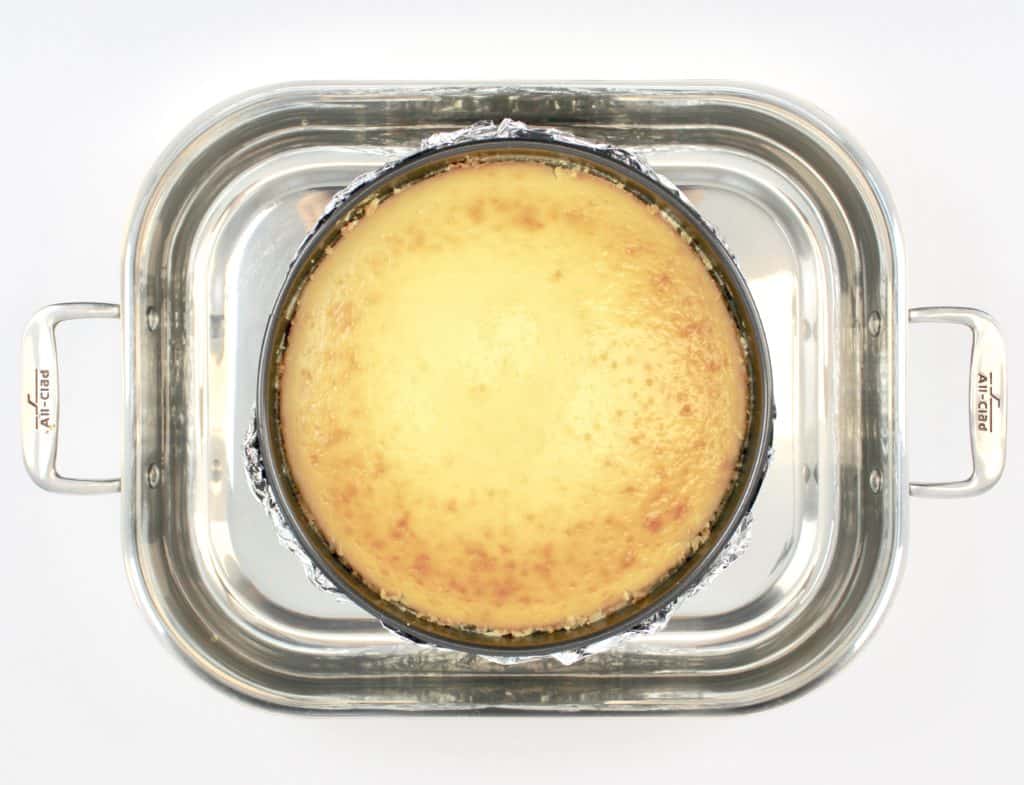 baked cheesecake in springform pan sitting in roasting pan