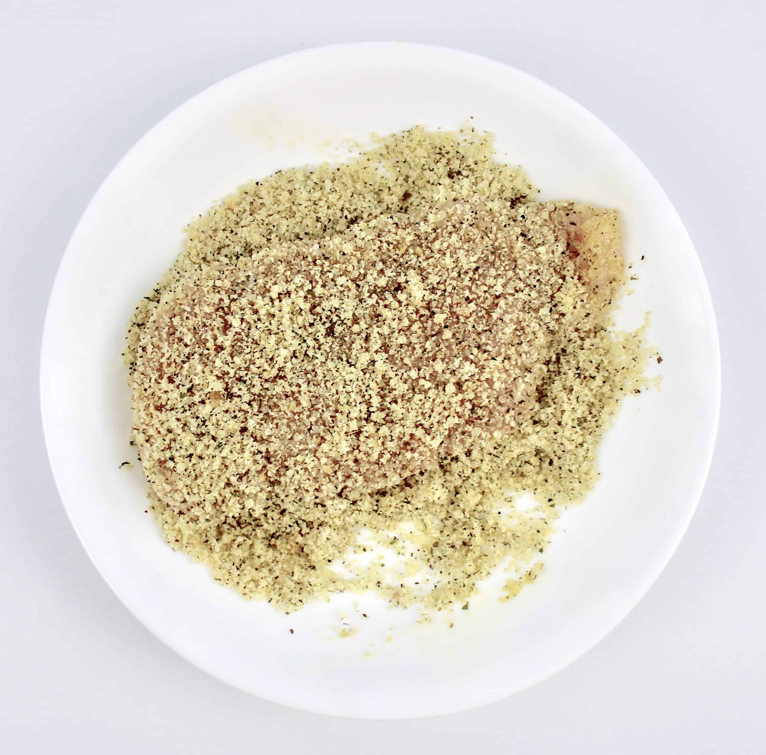 chicken breast in breading mixture in white plate
