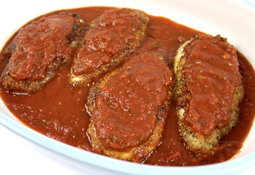 breaded chicken breasts in casserole with marinara sauce on top and bottom