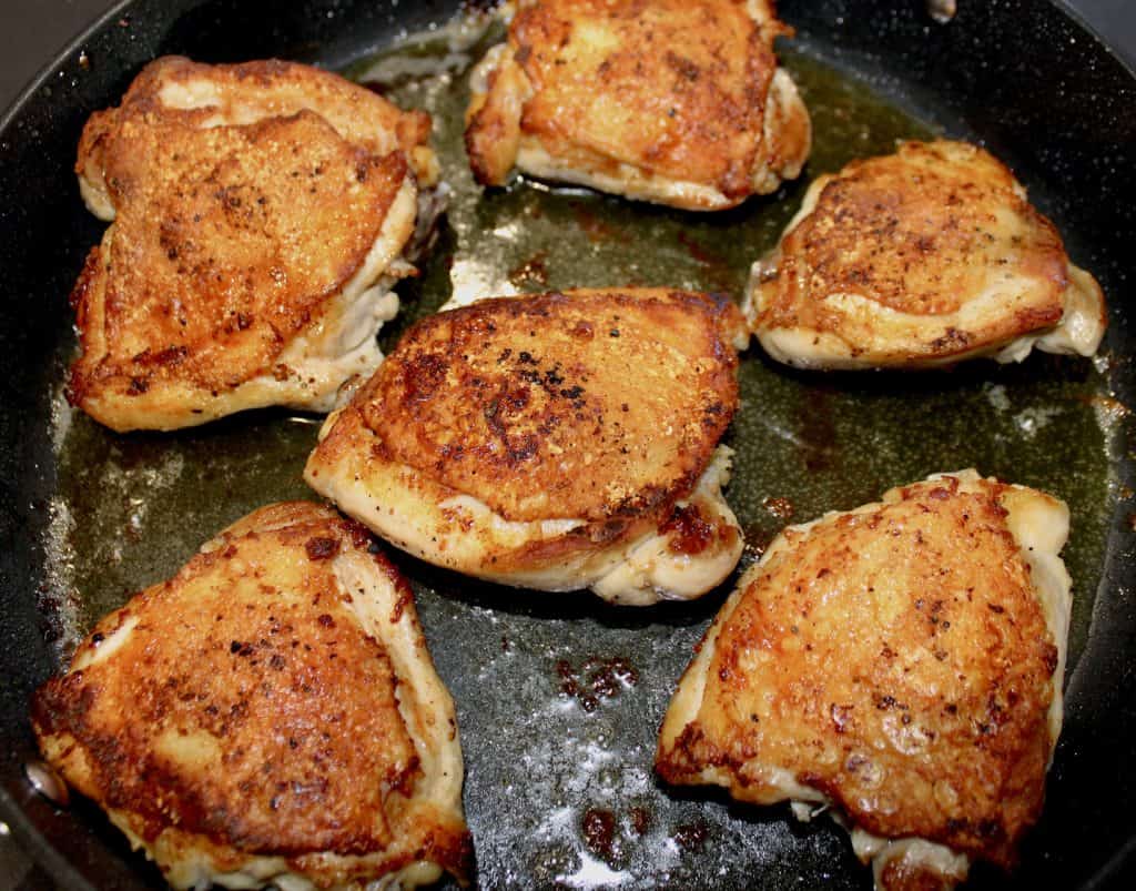 6 chicken thighs cooking in skillet