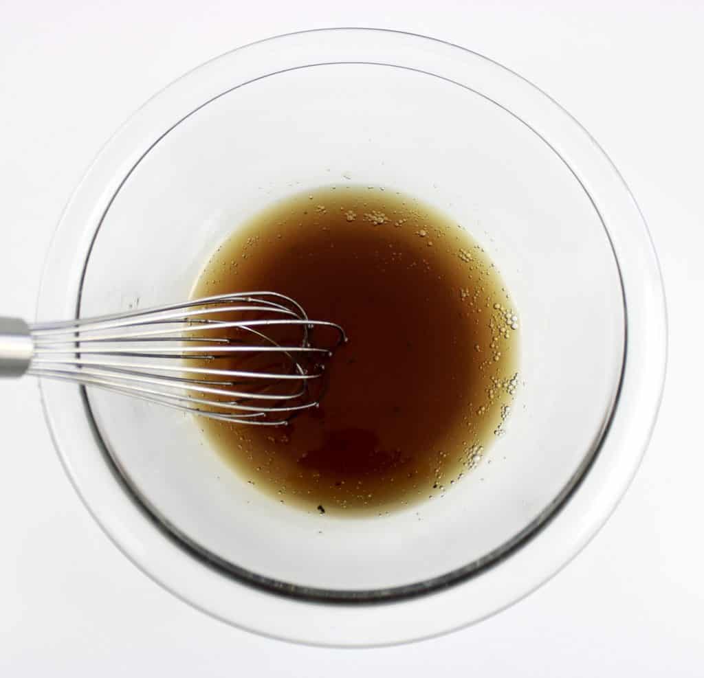 honey garlic chicken sauce in glass bowl with whisk