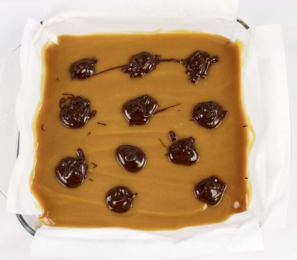 peanut butter fudge in baking dish with dollops of chocolate