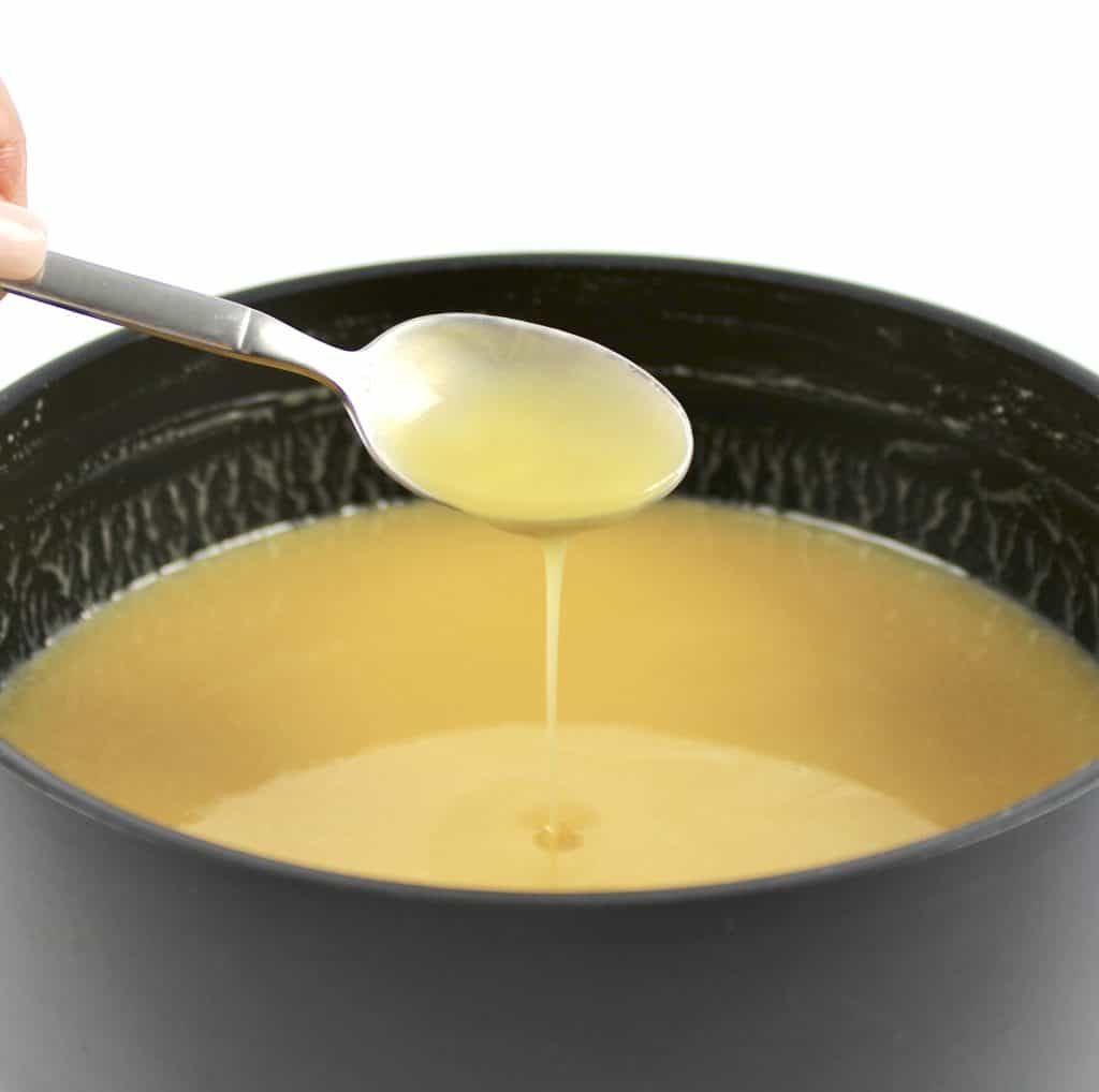 sweetened condensed milk being spooned out of saucepan