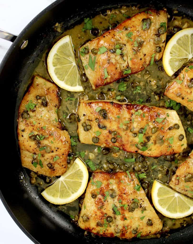 overhead view of skillet with pieces of snapper with lemon caper sauce