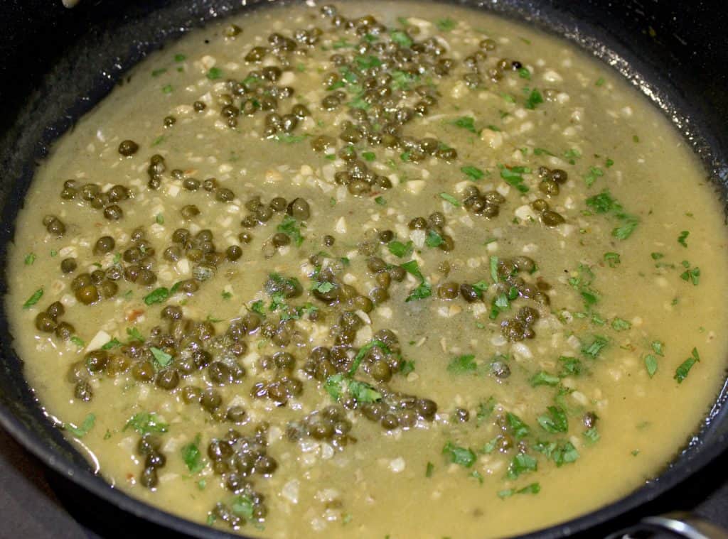 lemon caper sauce in skillet with chopped parsley
