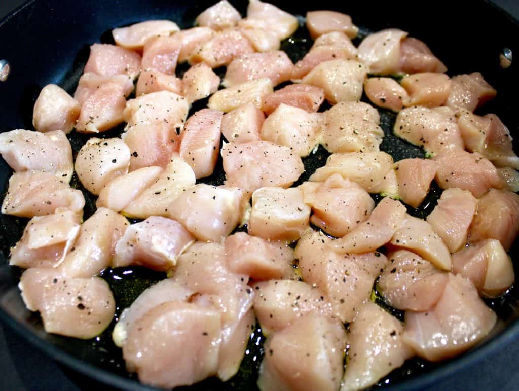 chunks of raw chicken in skillet