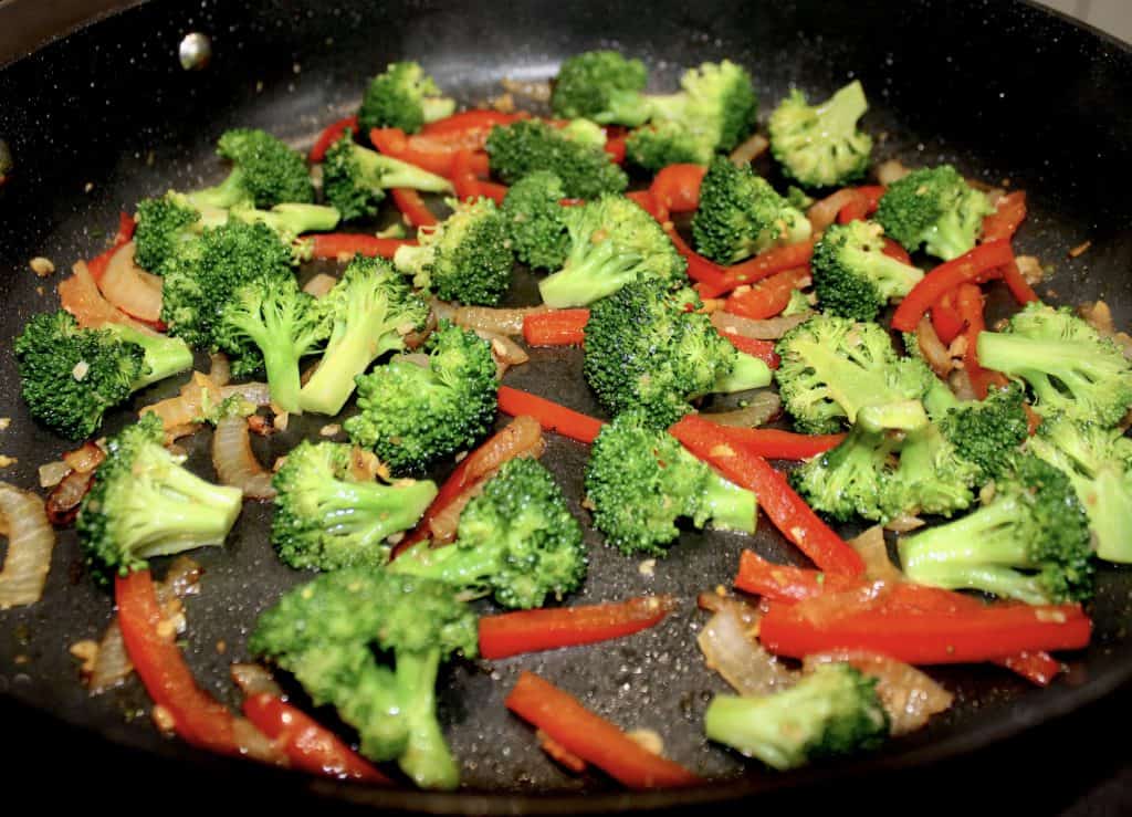 red bell pepper slices with onion and broccoli in skillet