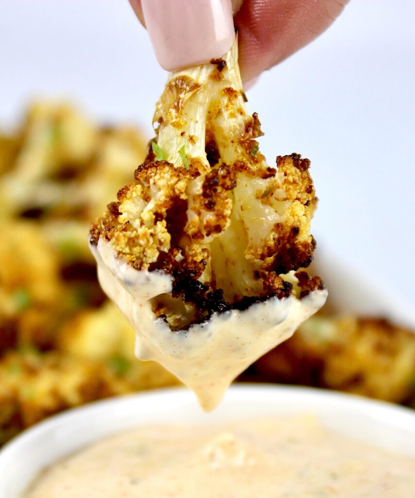 air fryer cauliflower being dipped into sauce