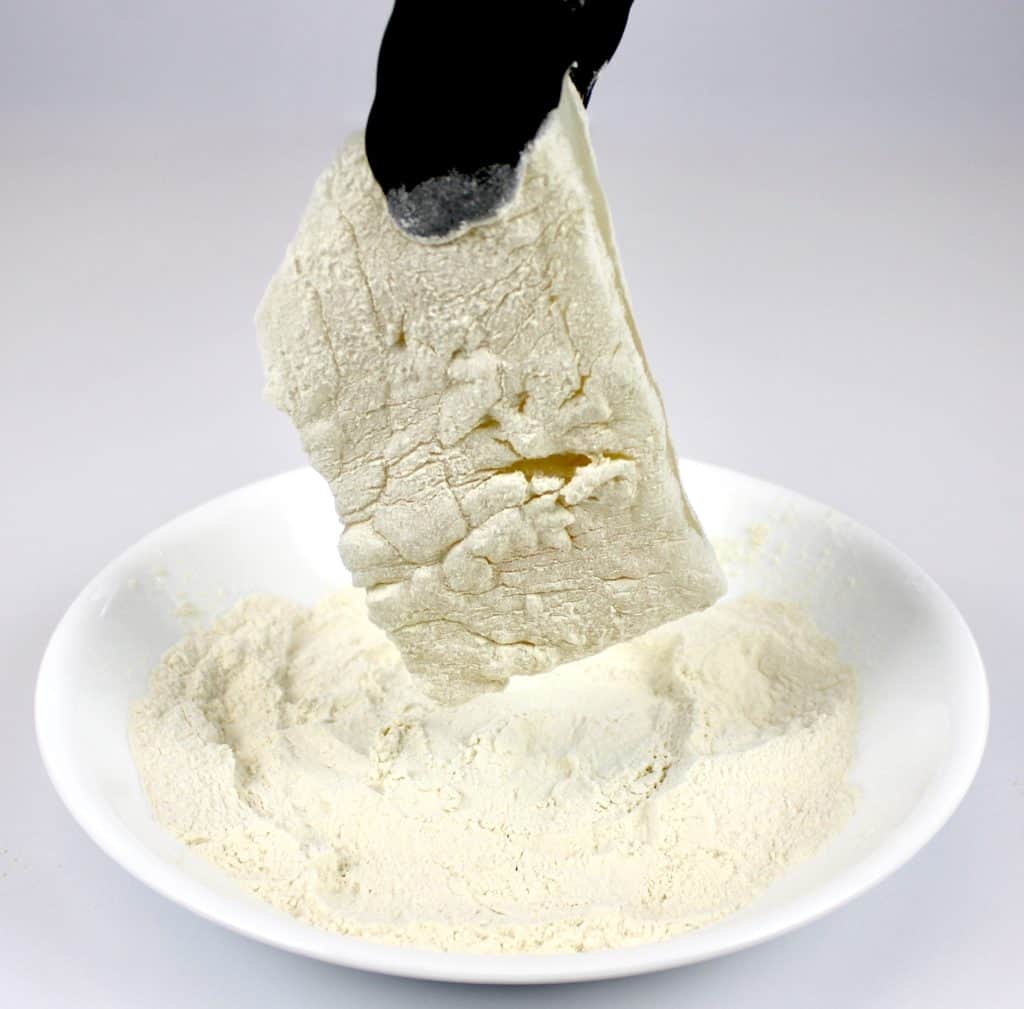 fish being dipped into oat fiber with black tongs
