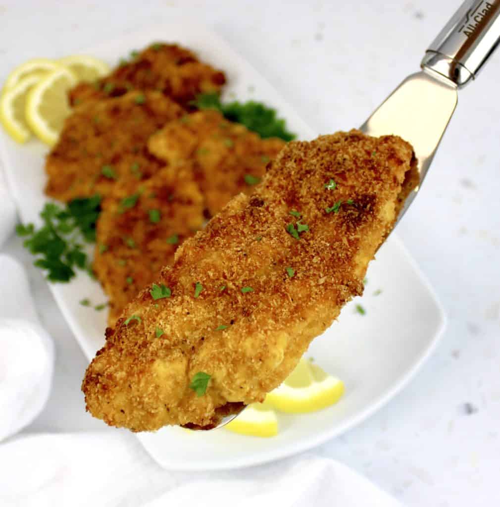 piece of fried cod held up with silver spatula