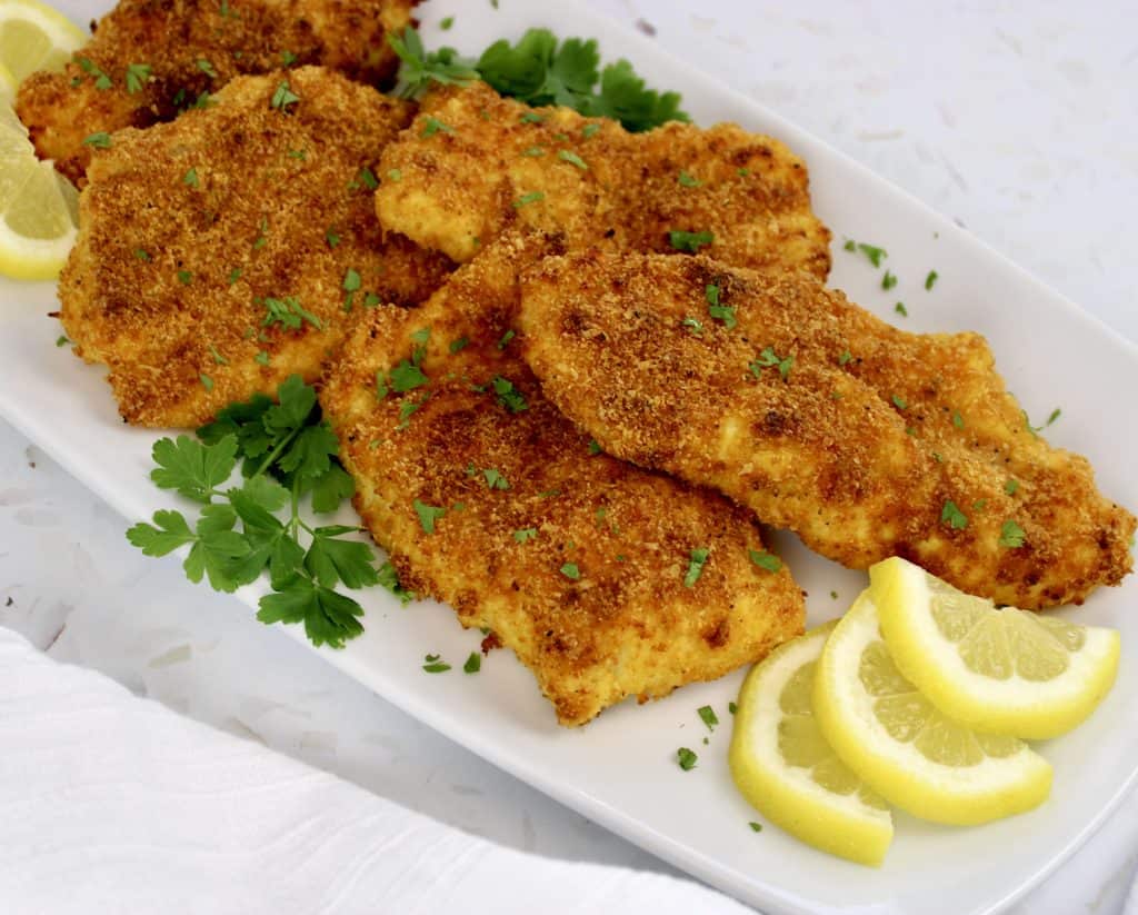 pieces of fried fish on white plate with slices of lemon