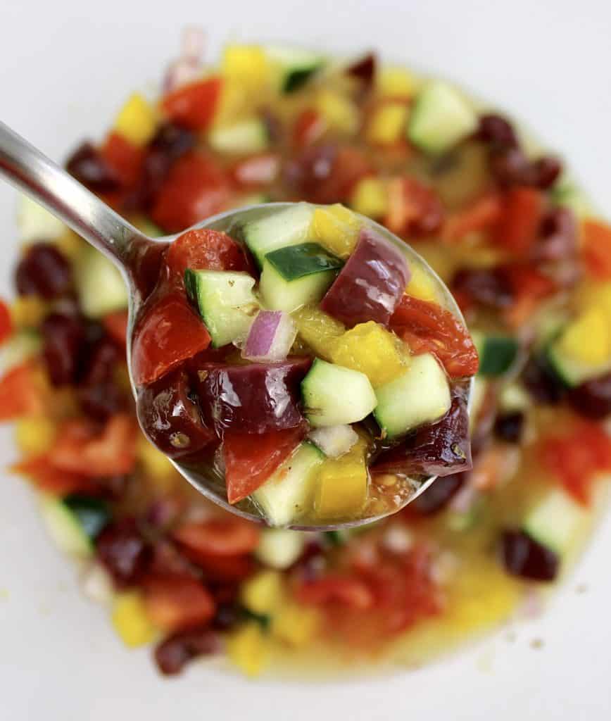 closeup of spoonful of Greek salsa over glass bowl