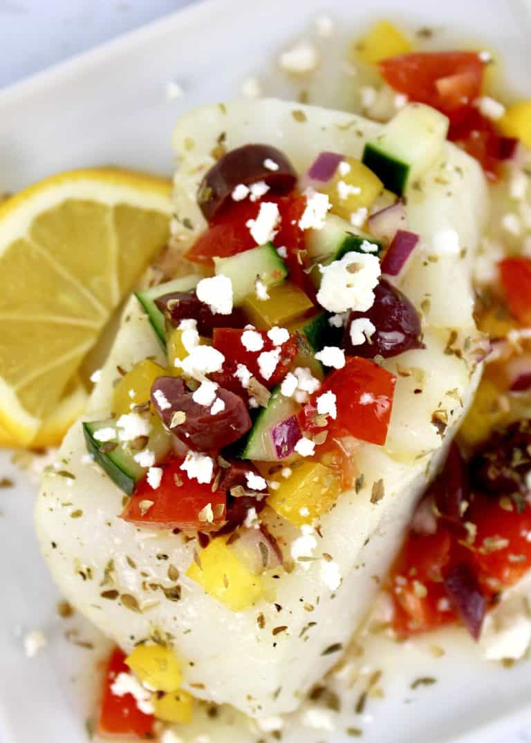 piece of cod with Greek salsa on top and lemon slices on side