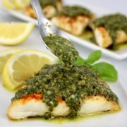 red snapper with pesto sauce being spooned over top