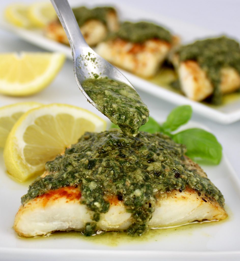 red snapper with pesto sauce being spooned over top