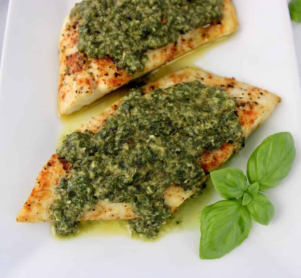 overhead view of snapper with pesto sauce on top basil on side