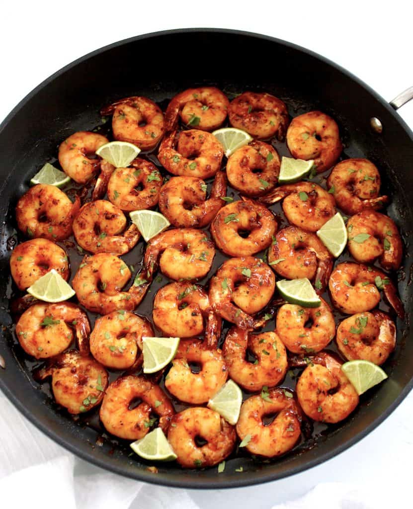 overhead view of Chili Lime Shrimp in skillet with wedges of lime