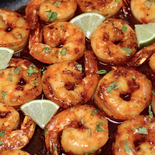 closeup of Chili Lime Shrimp with lime wedges