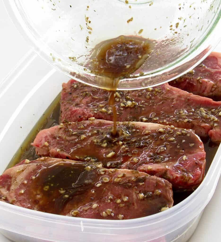 marinade being poured over 4 steaks in tupperware container