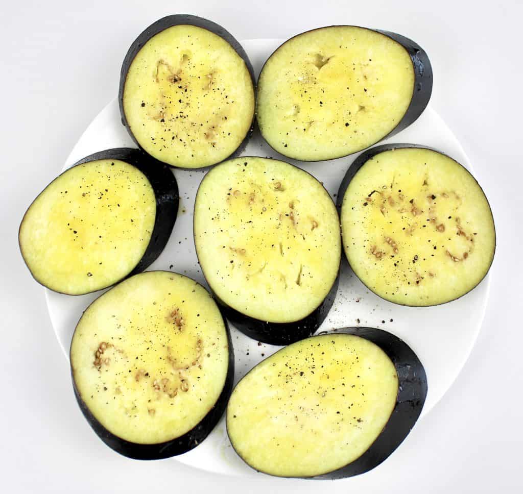 7 pieces of eggplant brushed with olive oil on white plate