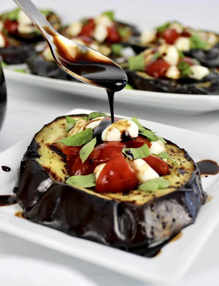 grilled eggplant with tomatoes mozzarella and balsamic being spooned on top