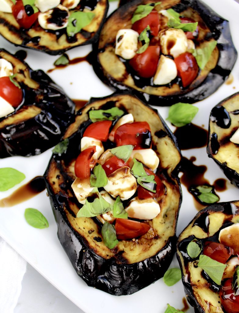 slices of grilled eggplant with tomatoes mozzarella and basil on top