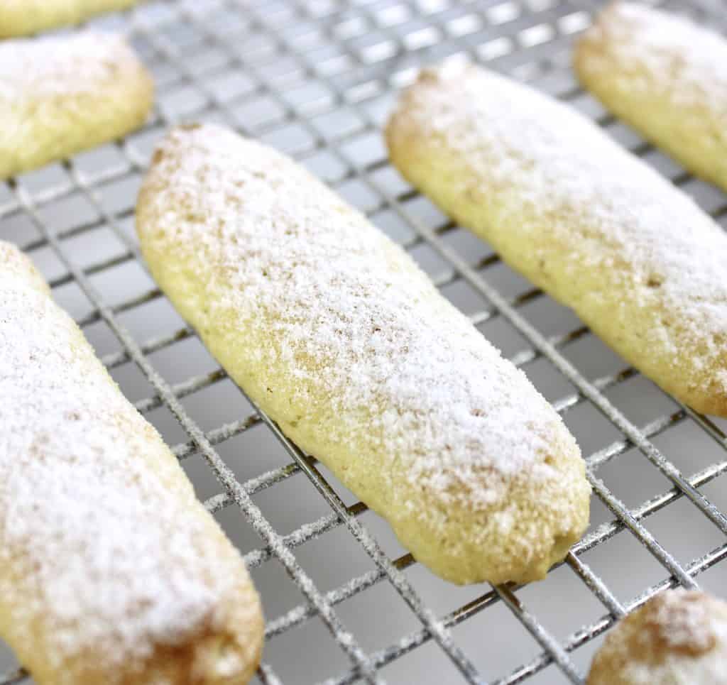 closeup of lady fingers on wire rack with powdered sugar on top