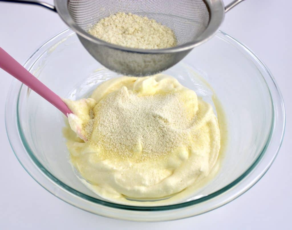 flour being sifted into beaten eggs mixture