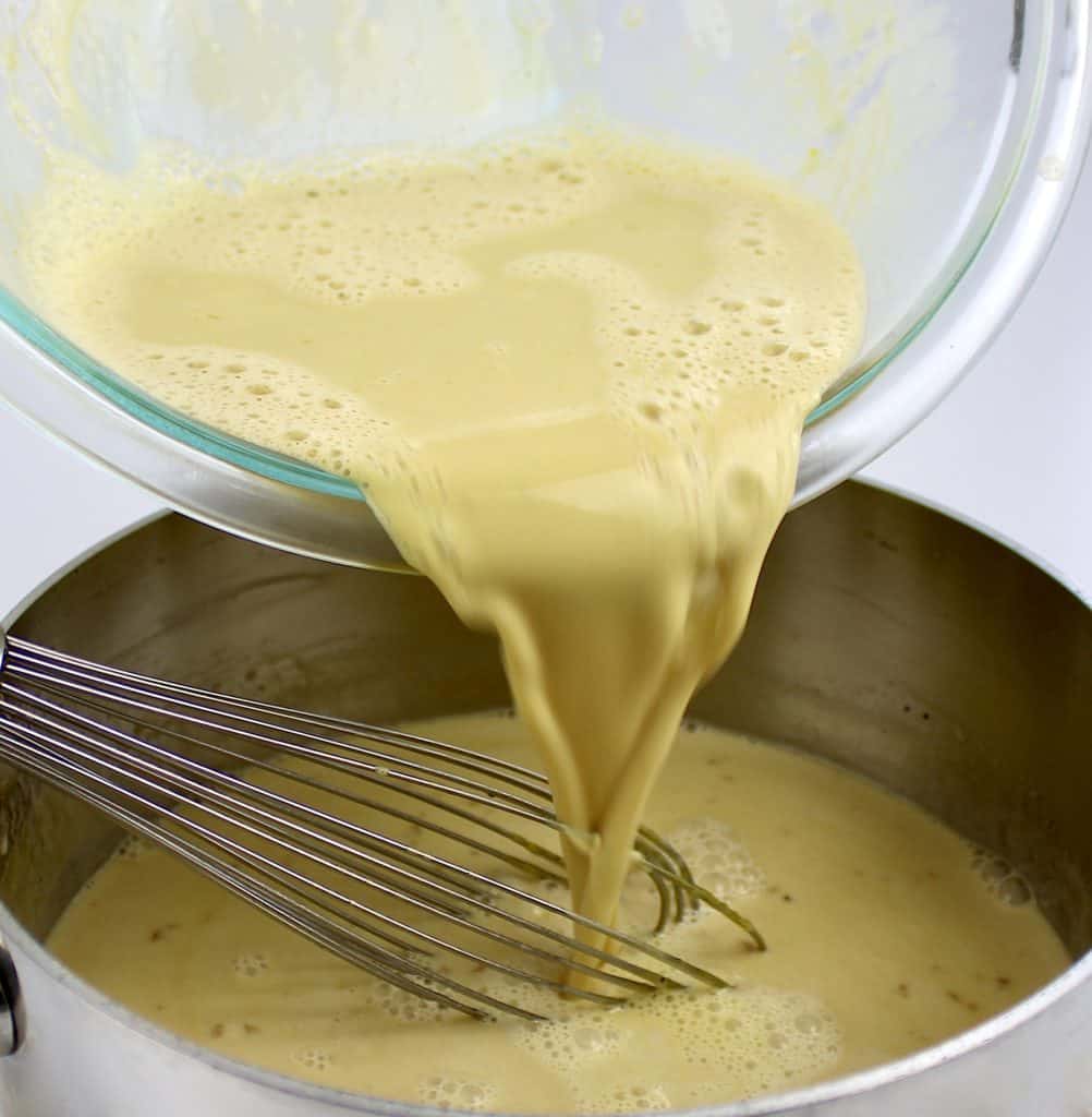 custard being poured and whisked into saucepan