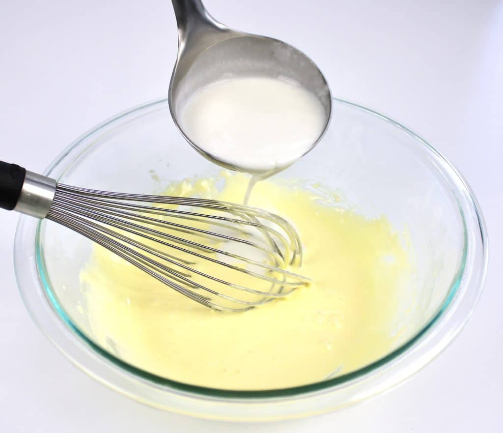 hot cream being ladled into glass bowl with whisk