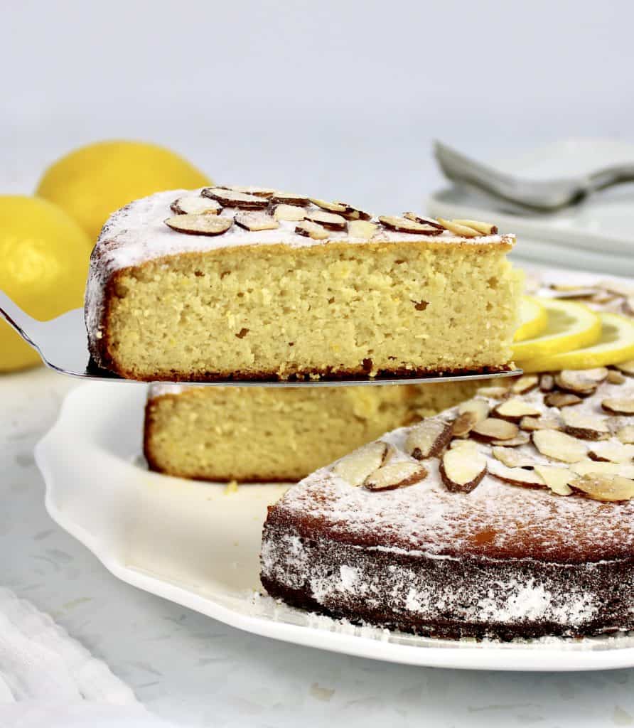 closeup of lemon ricotta cake slice being held up in front of cake