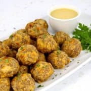 sausage balls on white plate with honey mustard on side