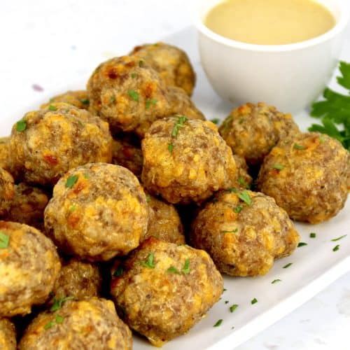 sausage balls on white plate with honey mustard on side