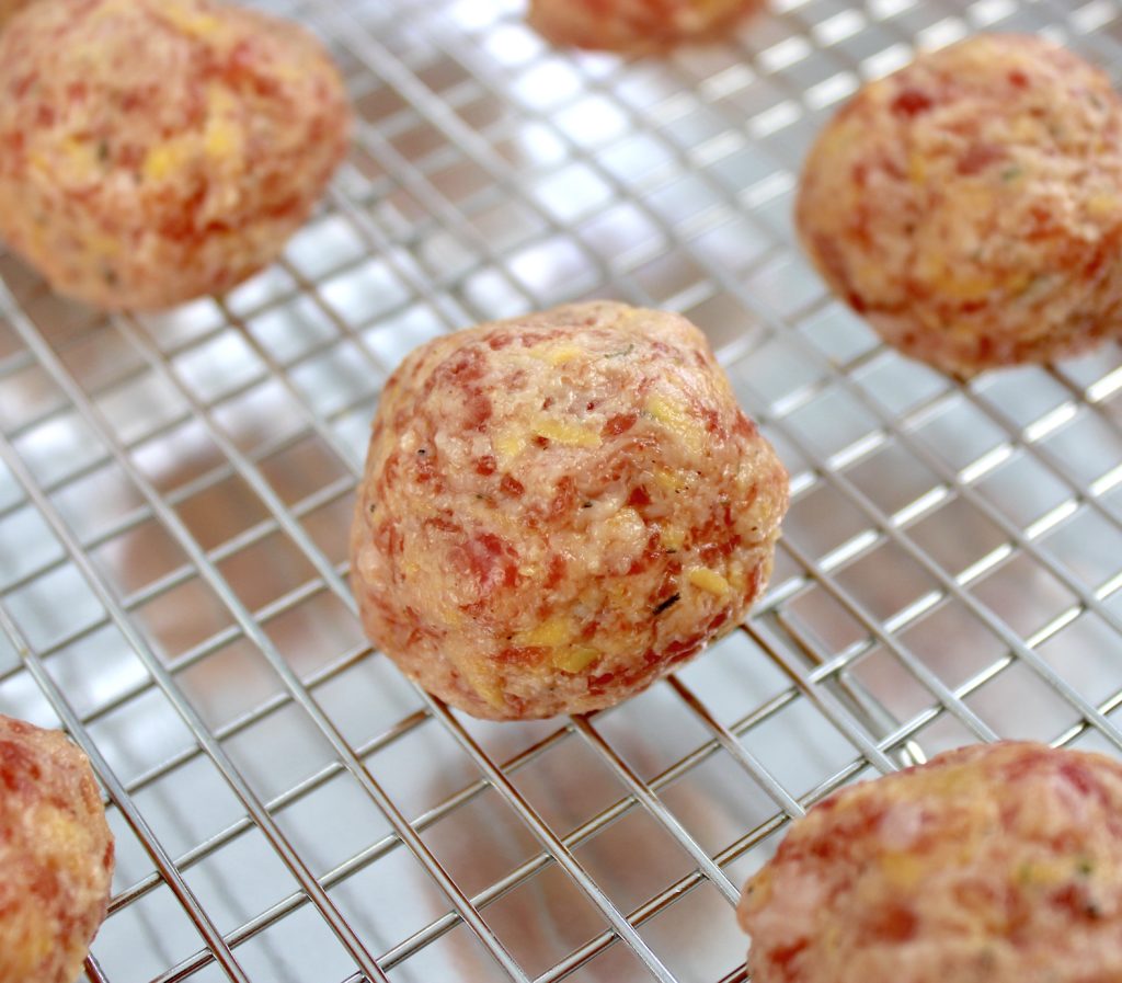 closeup of unbaked sausage balls on wire rack baking sheet