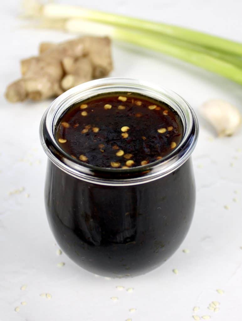 Keto Teriyaki Sauce in open glass jar with ginger and scallions in background